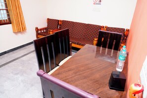 A dining area with a wooden table, chairs, and a bench. A bottle of water is on the table.