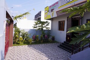 A residential building with a tiled entrance and a small garden with various plants. - Sri Sakthi Residence (Tiruvannamalai)