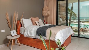 A modern bedroom with a large bed, a small side table, and a view of the ocean through large glass doors. - Fishermans Resort Life (La Libertad)