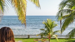 A poolside area with lounge chairs, a palm tree, and a view of the ocean. - Fishermans Resort Life (La Libertad)