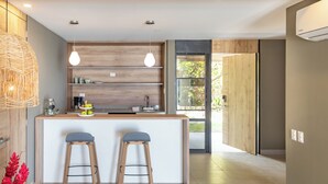 A modern kitchen with wooden shelves, pendant lights, and a bar area with stools. - Fishermans Resort Life (La Libertad)