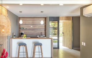 Una cocina moderna con estantes de madera, luces colgantes y una zona de bar con taburetes.