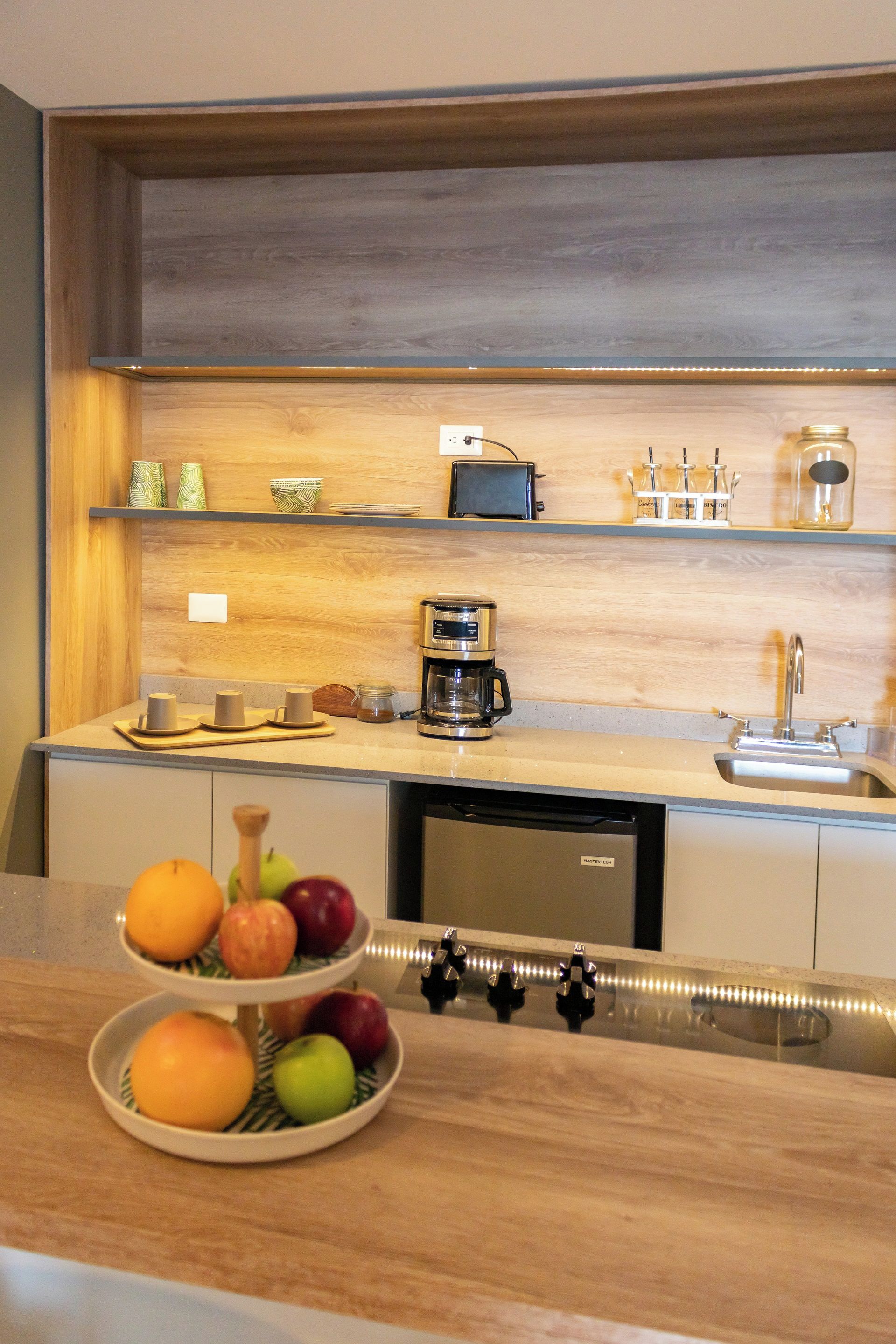 A kitchen with a wooden countertop, a coffee maker, a sink, and a fruit bowl.
