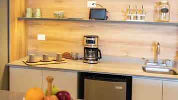 A kitchen with a wooden countertop, a coffee maker, a sink, and a fruit bowl.