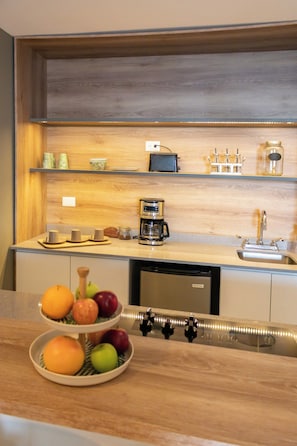 Una cocina con encimera de madera, cafetera, lavamanos y frutero.