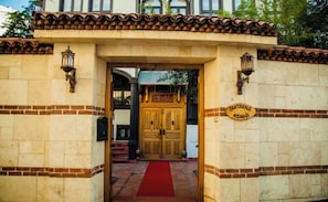 A building entrance with a red carpet, a wooden double door, and a sign reading 'TAHTAKALE KONAGI'.