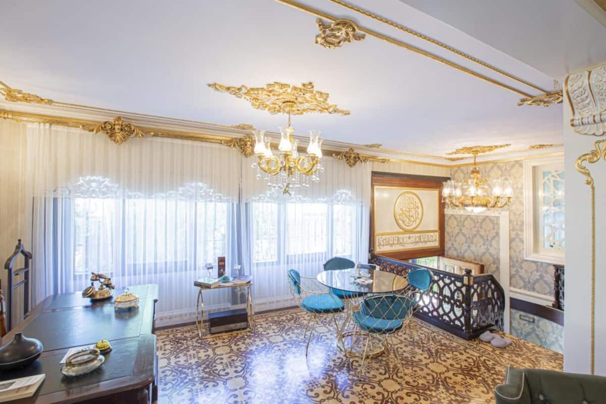 A room with a patterned floor, a chandelier, a table with chairs, and a decorative wall.