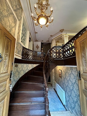 A grand staircase with ornate railings and a chandelier.