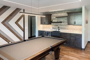 Una cocina moderna con mesa de billar, suelo de madera y armarios empotrados.