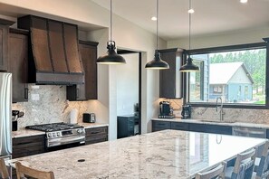 Una cocina moderna con armarios oscuros, una isla grande e iluminación colgante.