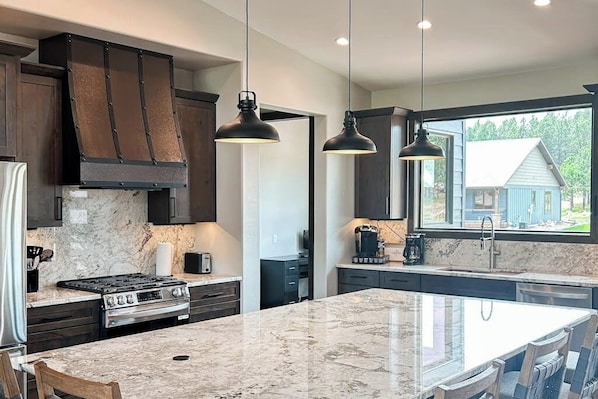 A modern kitchen with dark cabinetry, a large island, and pendant lighting.