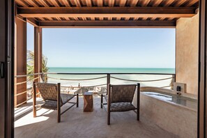 A balcony with two wicker chairs and a small table, overlooking a beach with a clear view of the ocean. - Awa Holbox Hotel Boutique - Beach Front (Isla Holbox)