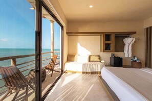 Een hotelkamer met balkon, een bed, zithoek en een kleine kitchenette.