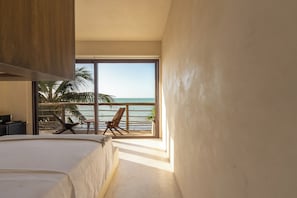 Un dormitorio con un ventanal grande, una cama y vista al océano.