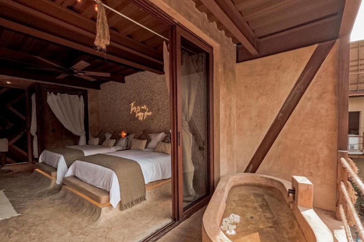 A bedroom with a large bed, a wooden ceiling, and a bathtub.