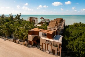 A beachfront property with a modern hotel named 'AWA HOTEL BOUTIQUE' featuring a mix of contemporary and traditional architecture, surrounded by lush greenery and a clear view of the ocean. - Awa Holbox Hotel Boutique - Beach Front (Isla Holbox)