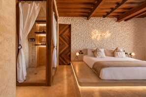 Une chambre à coucher comprenant un lit, une table de chevet, une lampe et un mur orné d’un motif texturé.