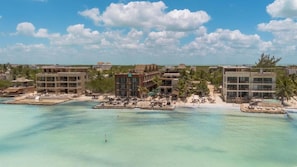 Un complejo turístico frente al mar, con varias edificaciones, una playa y aguas turquesas cristalinas.