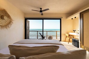 A bedroom with a large bed, a ceiling fan, a view of the sea, and a small desk with a chair. - Awa Holbox Hotel Boutique - Beach Front (Isla Holbox)
