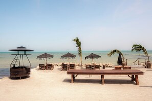 A beachside setting with a wooden table and chairs, a grill, and several umbrellas. - Awa Holbox Hotel Boutique - Beach Front (Isla Holbox)