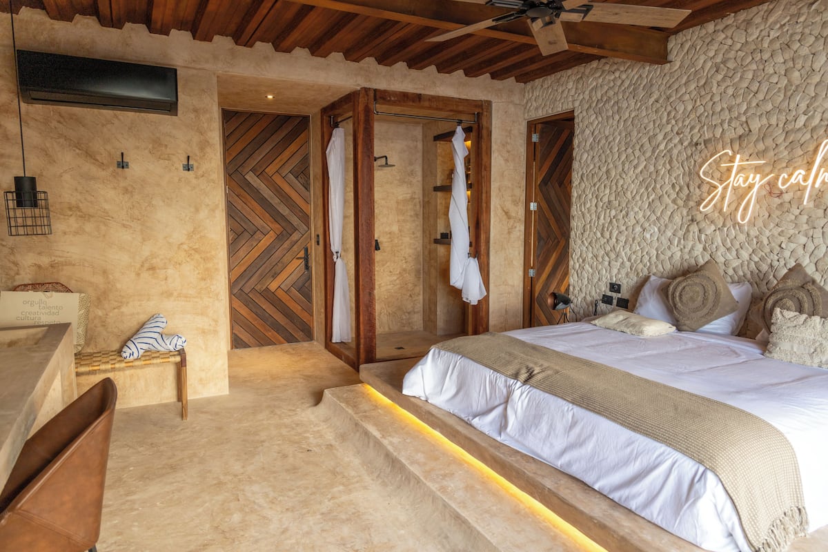 A bedroom with a bed, a wooden bench, a bench with a towel, and a wall with a herringbone pattern.