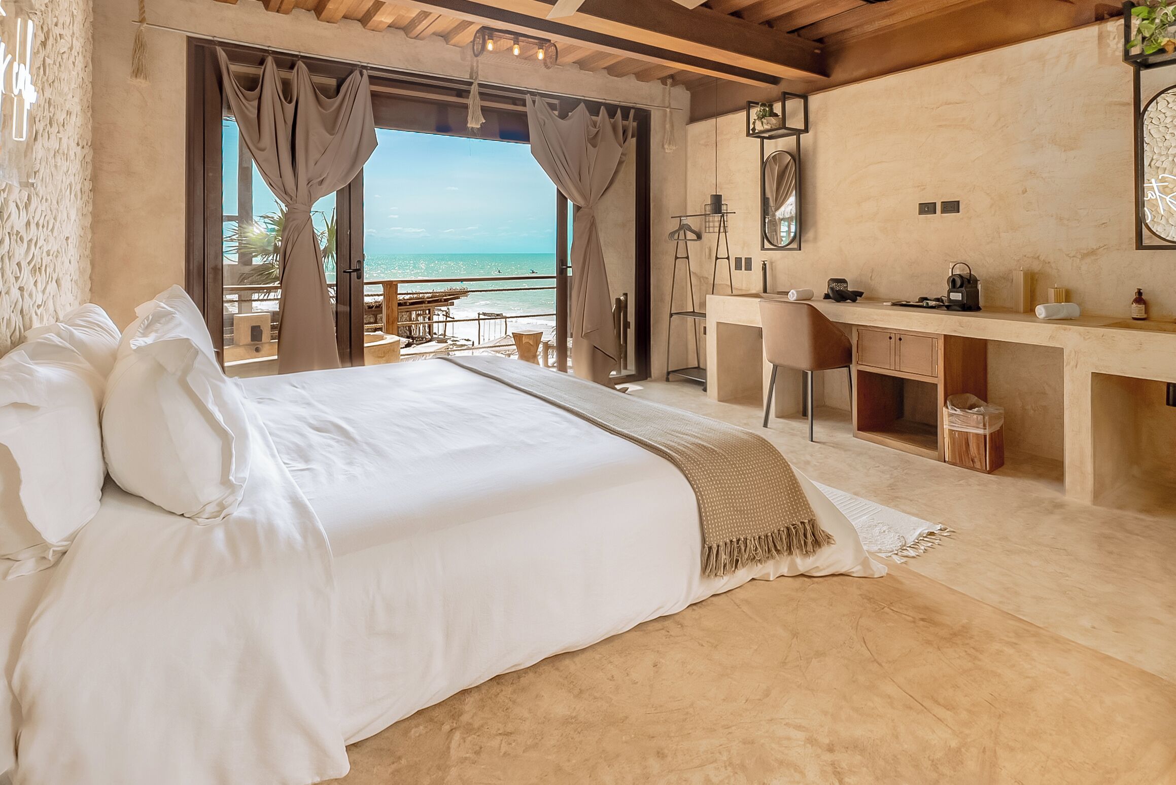 Une chambre avec un grand lit, un bureau et une vue sur la mer.
