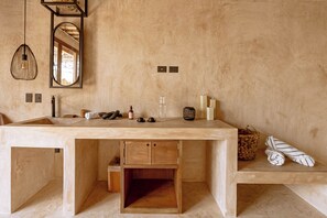 A modern bathroom with a large sink, wooden cabinets, a mirror, and a hanging light fixture. - Awa Holbox Hotel Boutique - Beach Front (Isla Holbox)