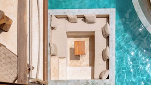 A poolside lounge area with a wooden table and beige cushions. - Awa Holbox Hotel Boutique - Beach Front (Isla Holbox)