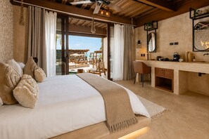 A bedroom with a large bed, a desk, and a view of an outdoor seating area. - Awa Holbox Hotel Boutique - Beach Front (Isla Holbox)