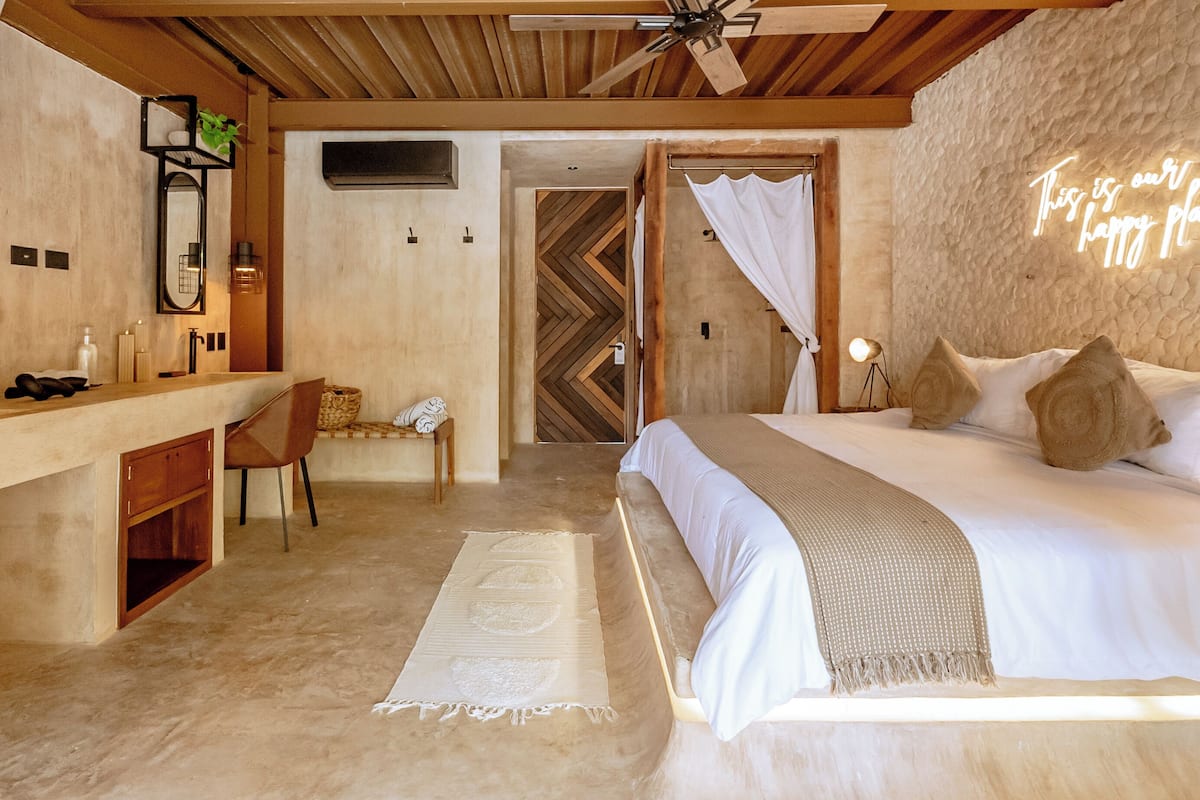 Une chambre à coucher avec un lit, une table de chevet, une chaise et un miroir.