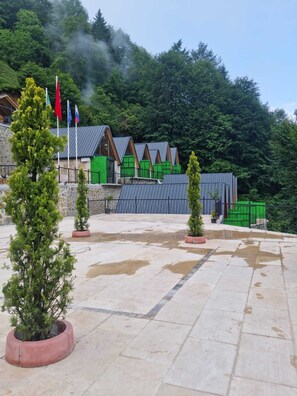 A building with a stone facade, green and red accents, and a metal roof. - Toli Bungalow Tatil Koyu (Pazar)