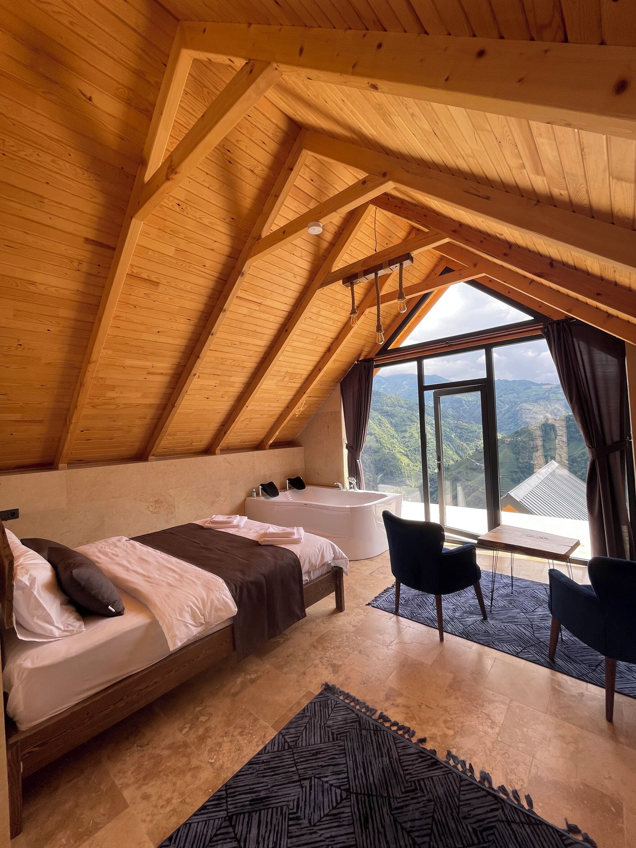Ein Schlafzimmer mit einem großen Bett, einer Badewanne und Blick ins Freie.