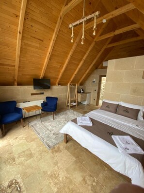A cozy attic bedroom with a sloped ceiling, a bed, a desk, a chair, and a TV mounted on the wall. - Toli Bungalow Tatil Koyu (Pazar)