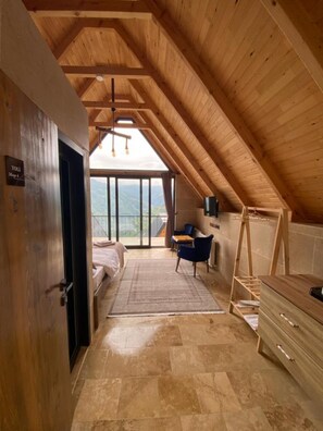 A high-ceilinged room with a wooden ceiling, a bed, a desk, and a view of the outdoors. - Toli Bungalow Tatil Koyu (Pazar)