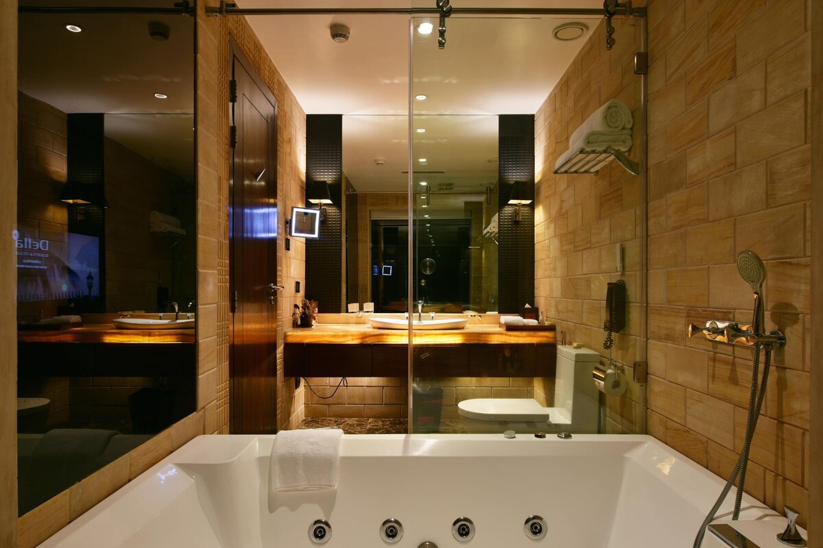 A modern bathroom with a large bathtub, a shower, and a vanity with a mirror.