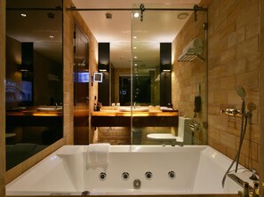 A modern bathroom with a large bathtub, a shower, and a vanity with a mirror. - Della Resorts Lonavala (Mawal)