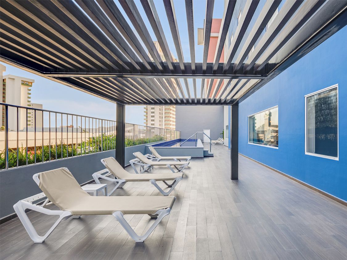 A rooftop terrace with lounge chairs, a pool, and a view of the cityscape.
