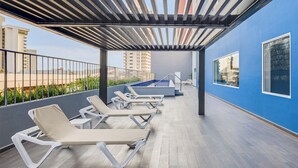 A rooftop terrace with lounge chairs, a pool, and a view of the cityscape. - One Mazatlán (Mazatlan)