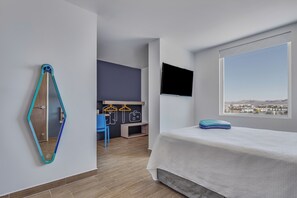 A modern bedroom with a bed, a TV, a large window, a mirror, and a desk with a chair. - One Mazatlán (Mazatlan)