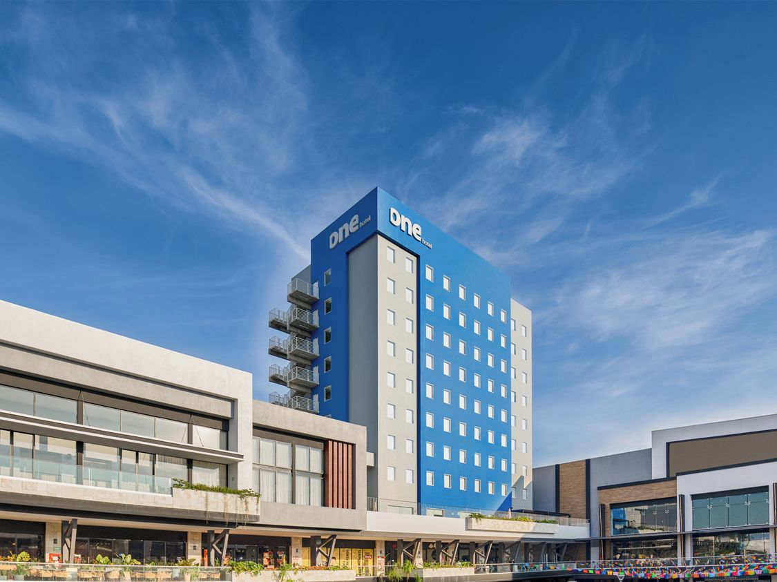 Un hotel modern amb una façana destacada de blau i blanc, diversos pisos i un terrat pla.