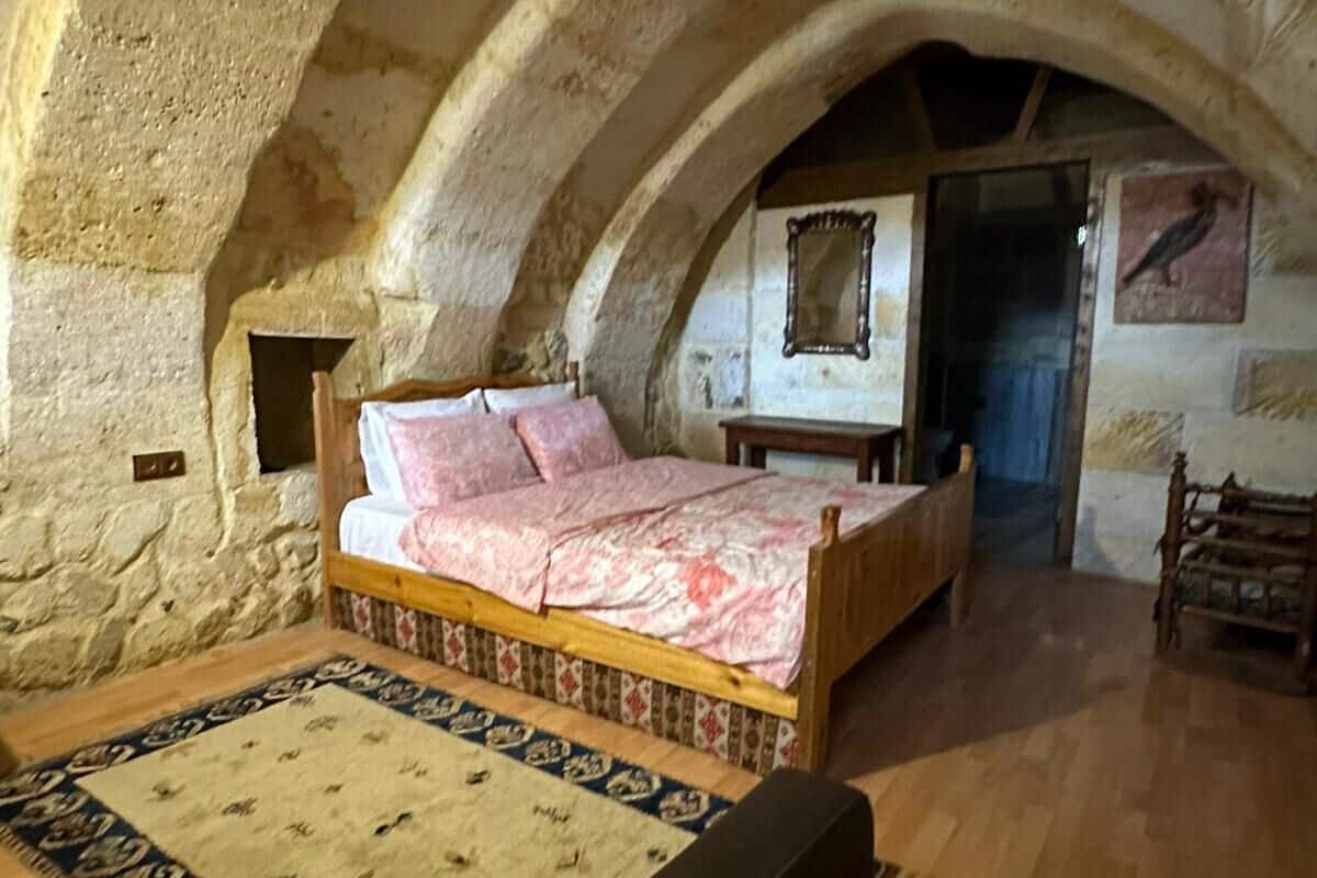 A bedroom with a bed, a wooden bench, a mirror, and a stone wall.