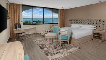 Habitación de hotel con una ventana grande, una cama, un escritorio y dos sillas.