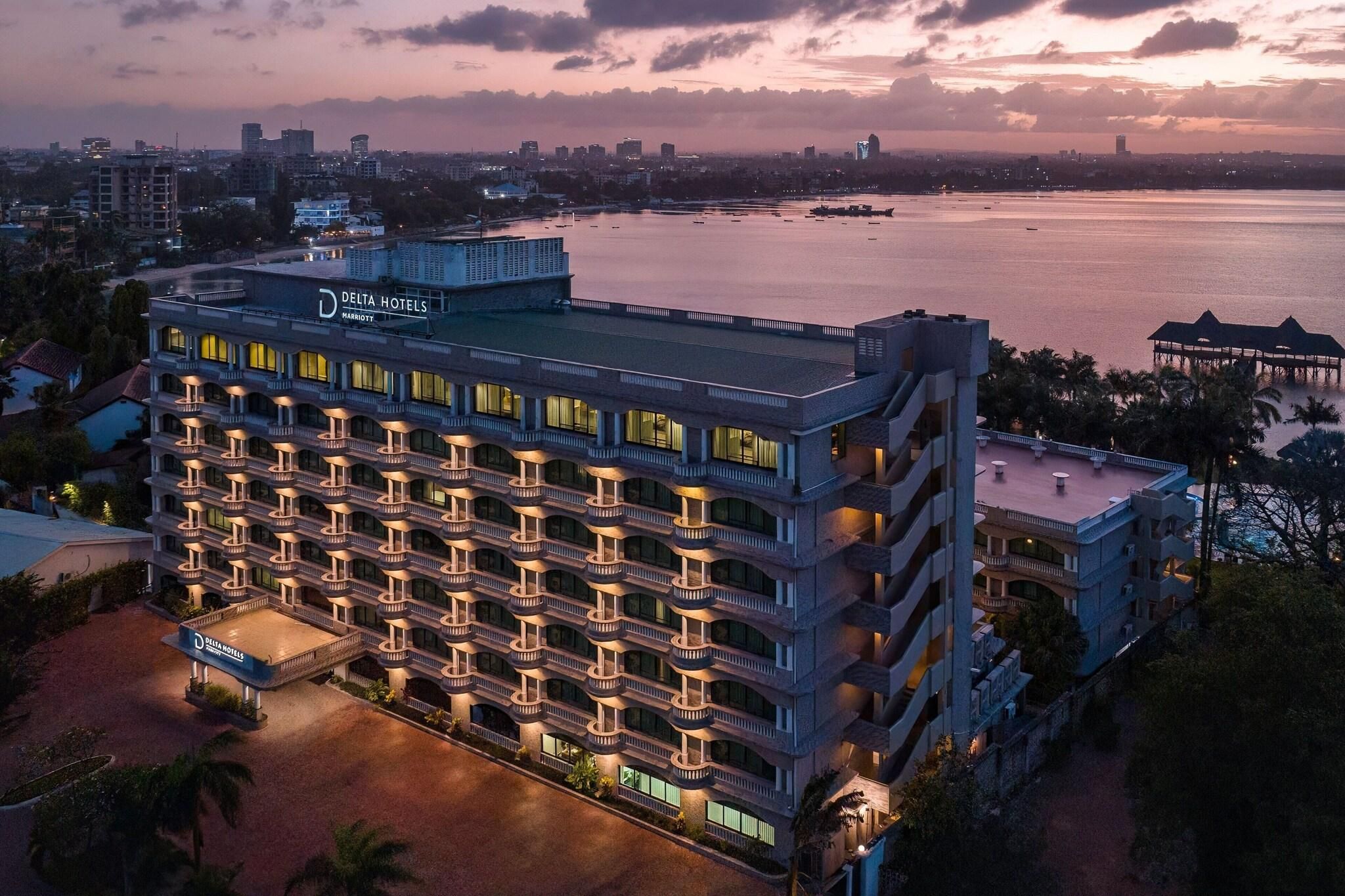 A multi-story hotel with balconies, a pool, and a view of the water.