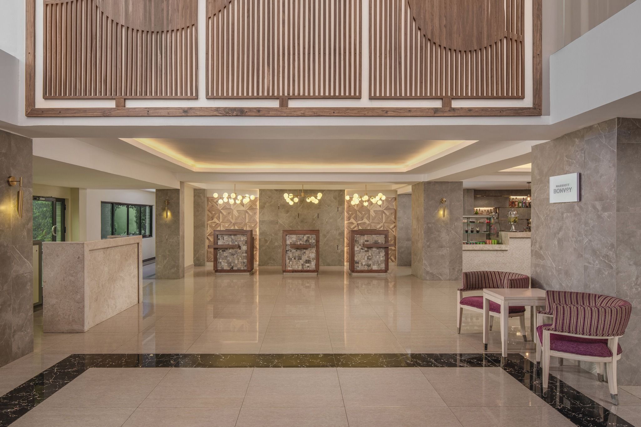 A hotel lobby with a reception desk, seating area, and a bar.