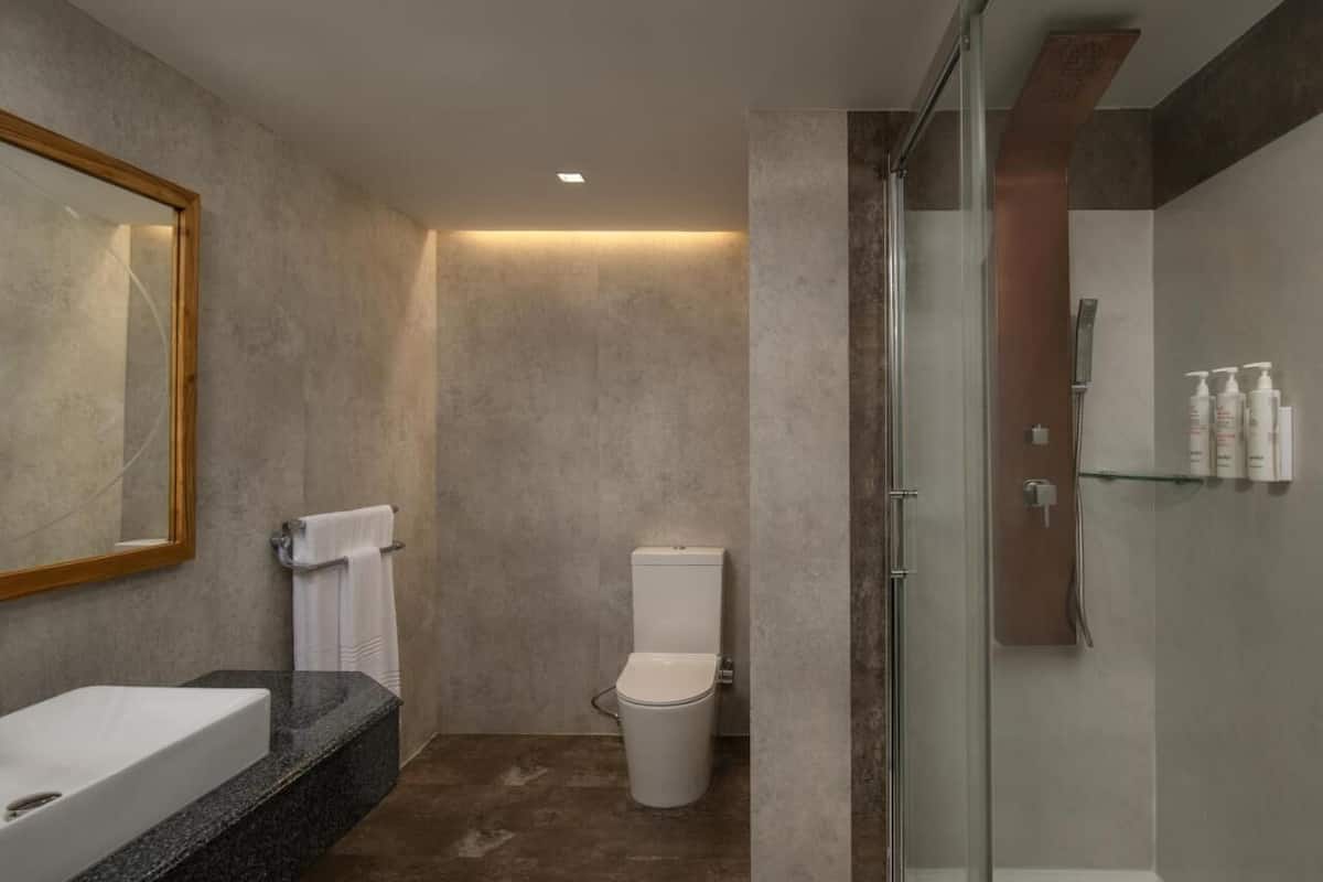 Un baño moderno con un espejo grande, una bañera, un inodoro y una cabina de ducha de cristal.