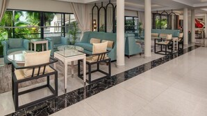 A spacious lobby with a seating area featuring sofas and chairs, large windows with curtains, and a view of greenery outside. - Delta Hotels Marriott, Dar es Salaam (Dar es Salaam)