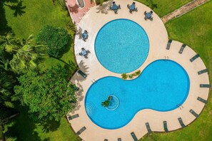 An aerial view of a resort with two circular pools, surrounded by lounge chairs and palm trees. - Delta Hotels Marriott, Dar es Salaam (Dar es Salaam)