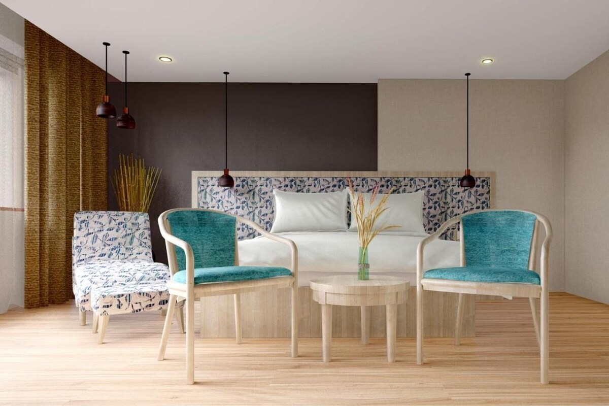 A modern room with a bed, two chairs, a small table, and a large window with curtains.