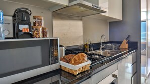 A modern kitchen with a built-in microwave, toaster, and oven, a bread basket, and a knife block.