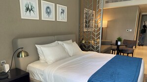 A hotel room with a bed, bedside table, lamp, and artwork on the wall.